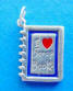 Sterling silver scrapbook charm with blue and red enamel and says I love scrapbooks
